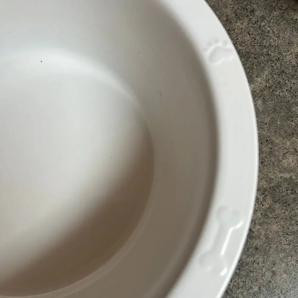 Enamel dog food or water bowl. Paw prints & bones adorn rim